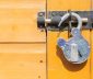 Unlocked padlock securing a latch on a yellow door
